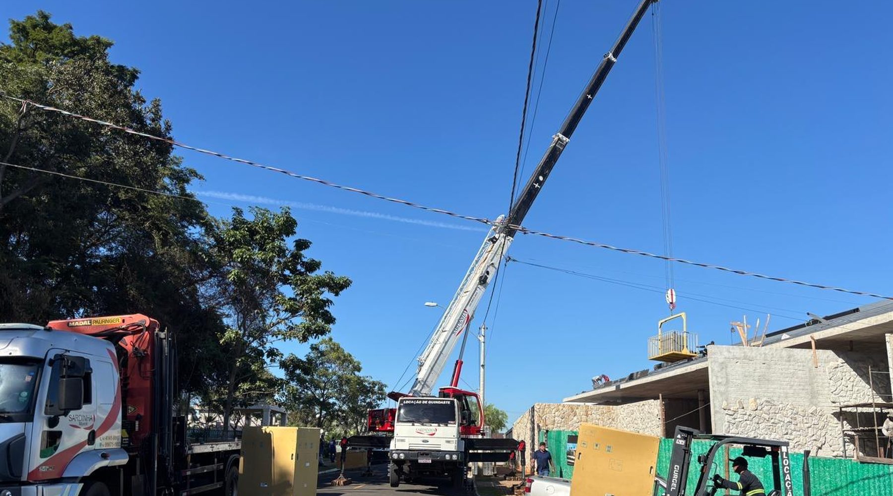 Dois caminhões munck da Sardinha em operação de içamento em avenida de Bauru